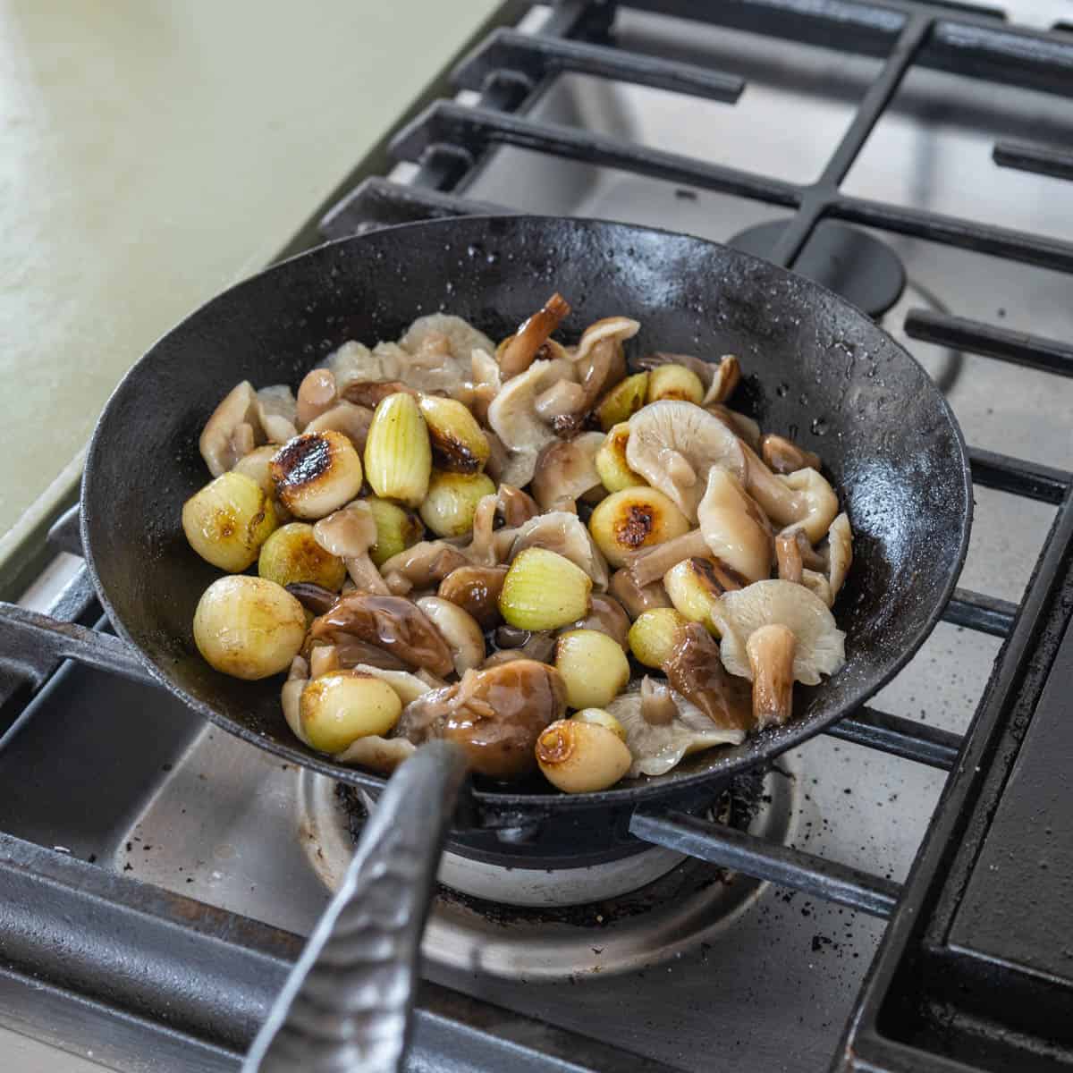 Sauteeing mushrooms and pearl onions in a pan.