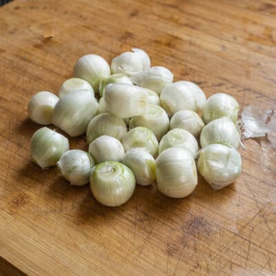 Pearl onions on a cutting board after trimming and peeling. 