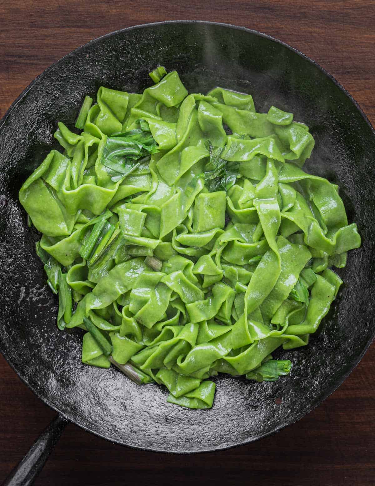 Bright green ramp pasta in a saute pan with ramp leaves and butter.