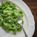 a plate of green ramp pasta with butter and parmesan on a plate with a fork.