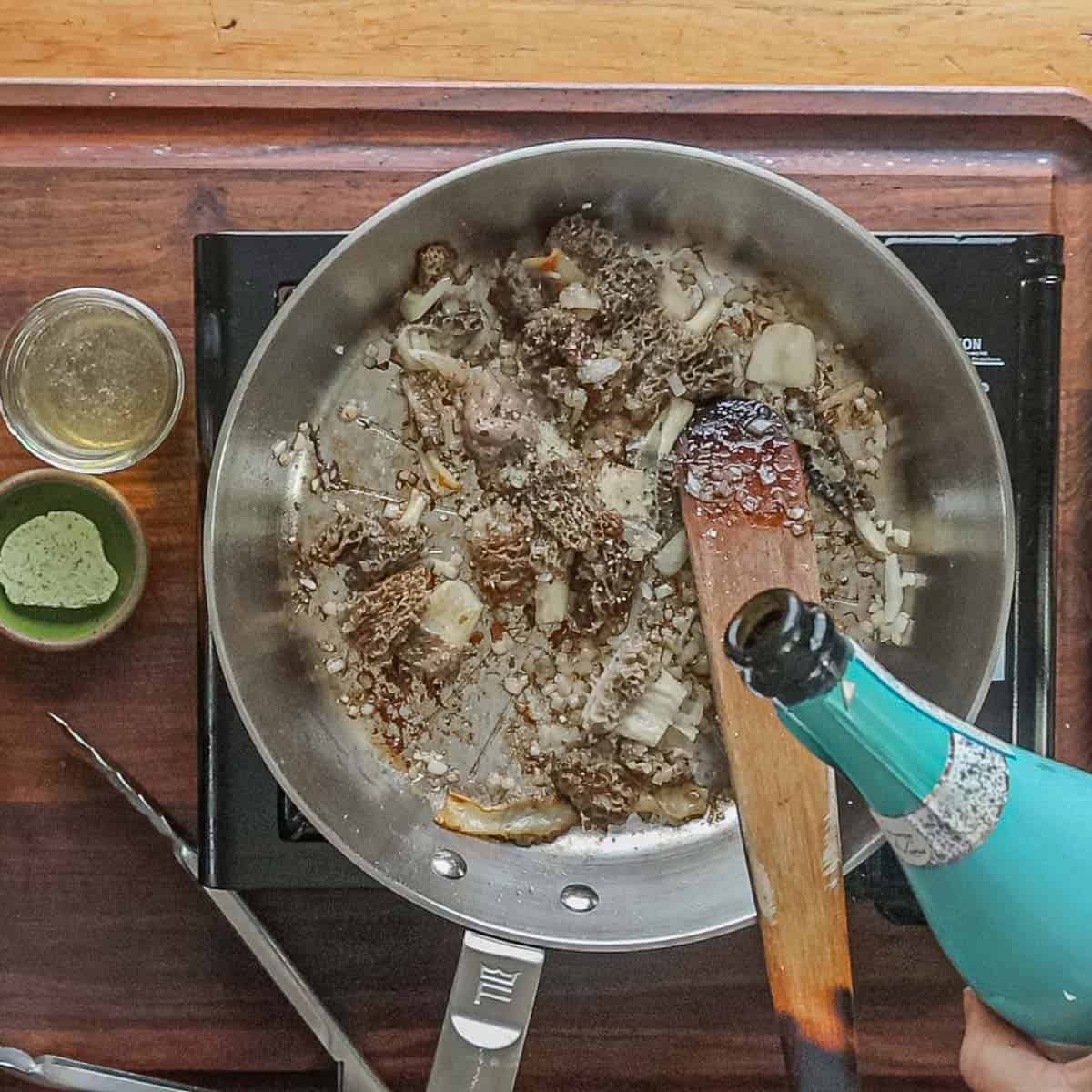 Add white wine to a pan of morel mushrooms and ramps. 