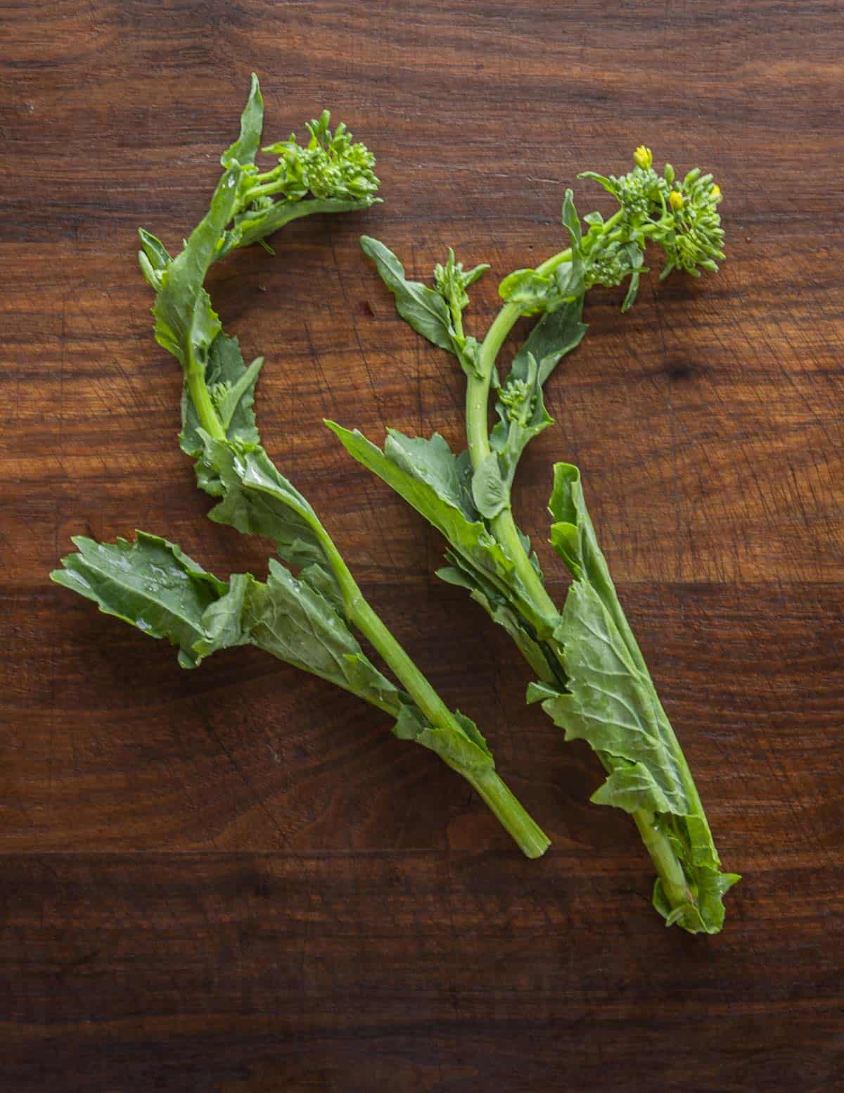 Rapini or broccoli rabe stalks on a cutting board.
