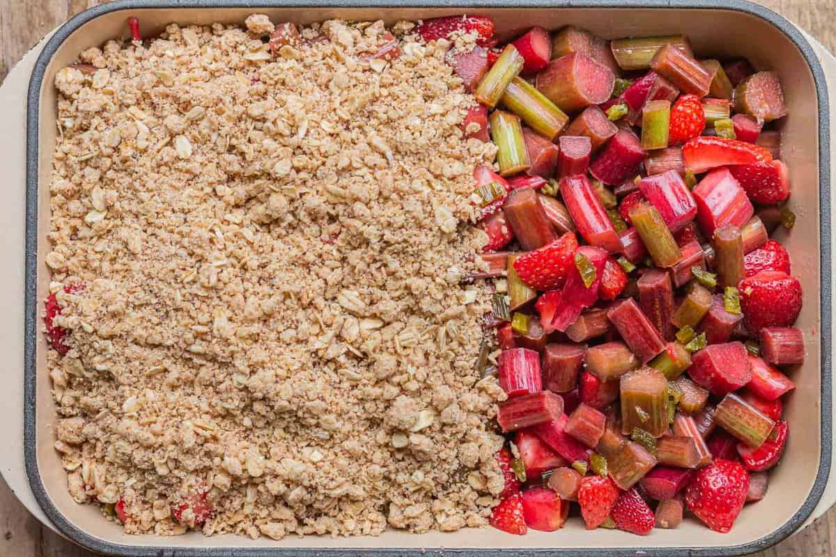 strawberry rhubarb crisp being covered by a crumb topping. 