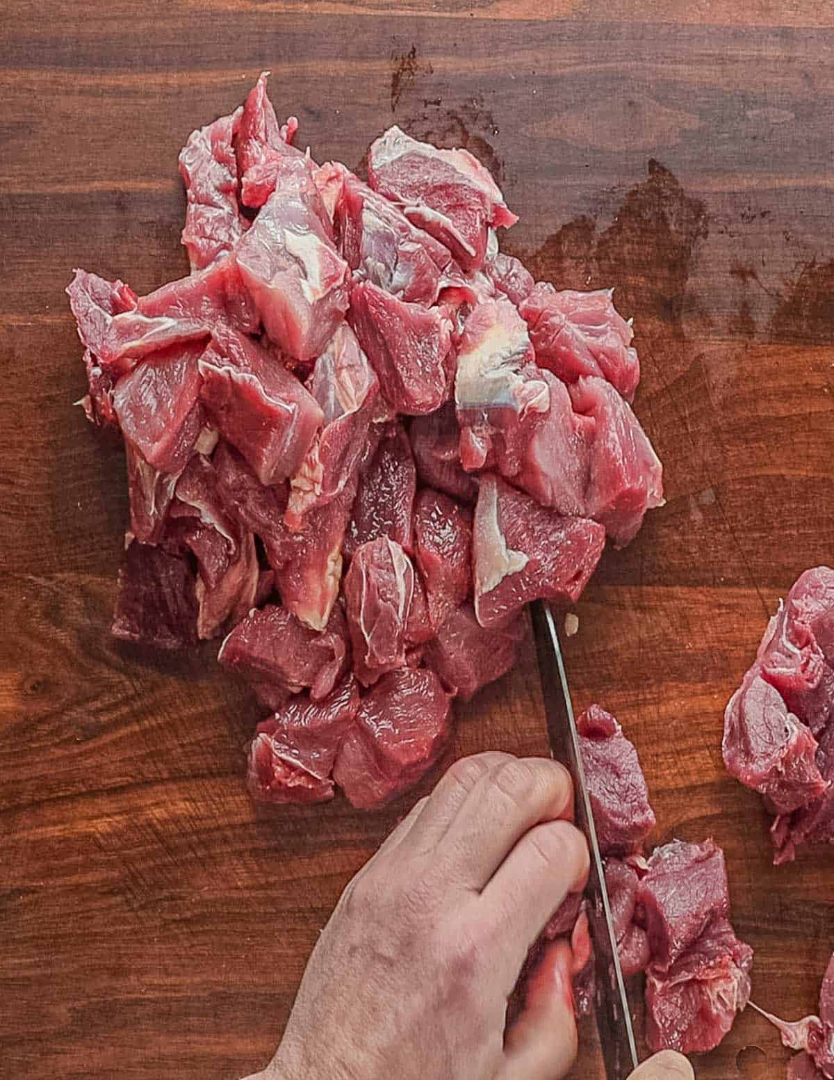 Cutting wild boar shoulder into large pieces for a meat grinder. 