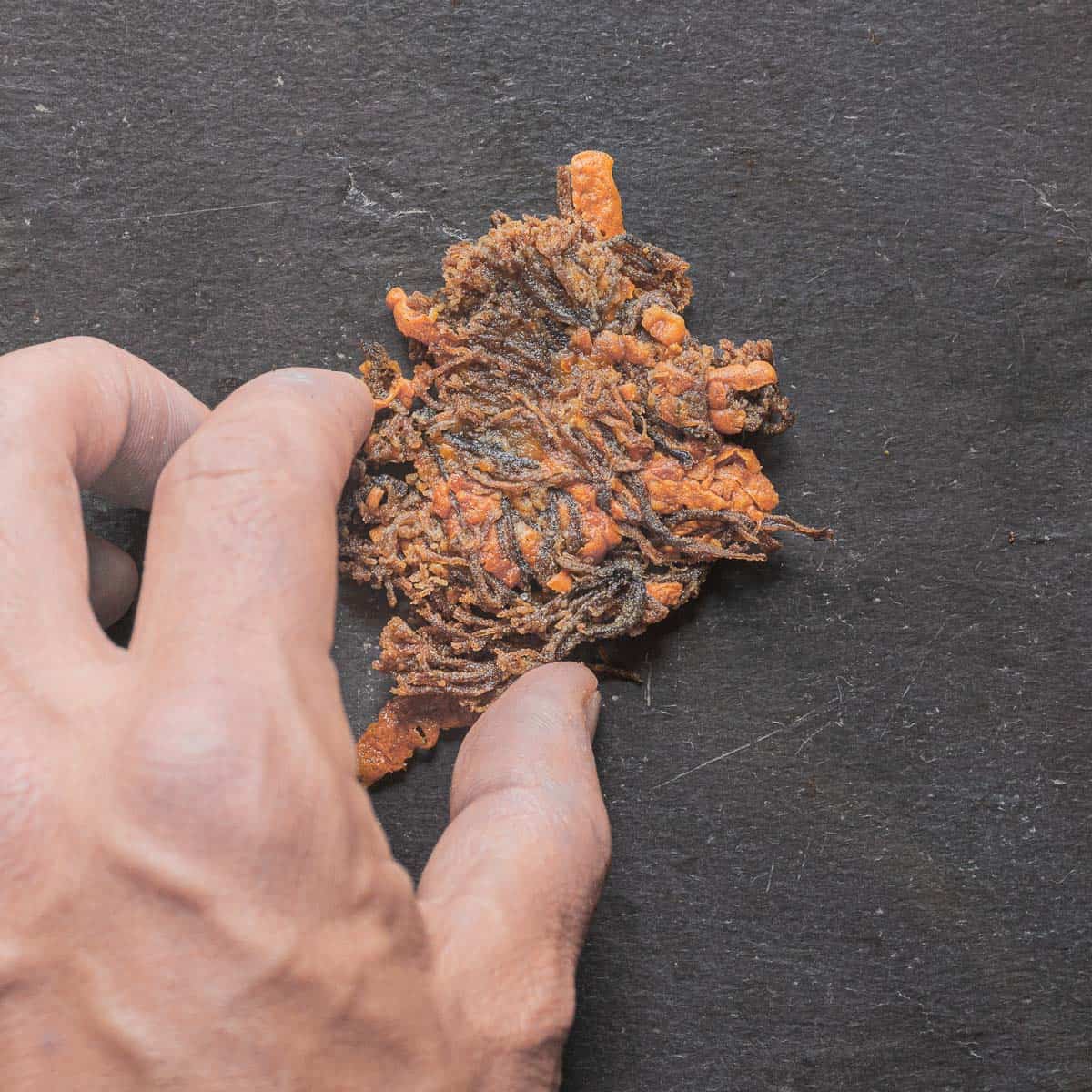 A hand grabbing crown tipped coral mushroom crackers. 