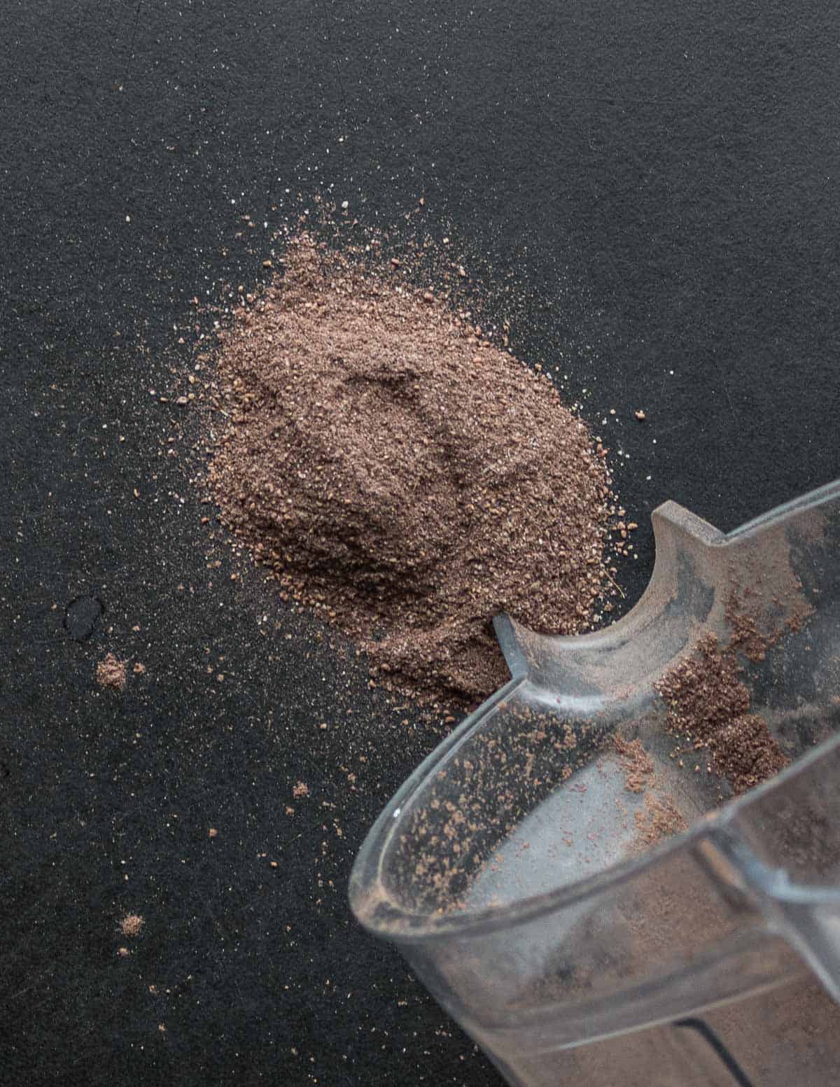 Ground dock seed flour being poured out of a blender. 