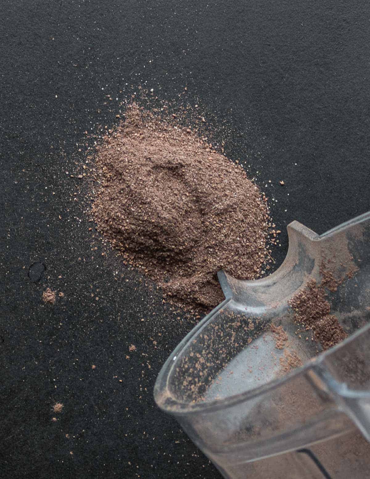 Ground dock seed flour being poured out of a blender.