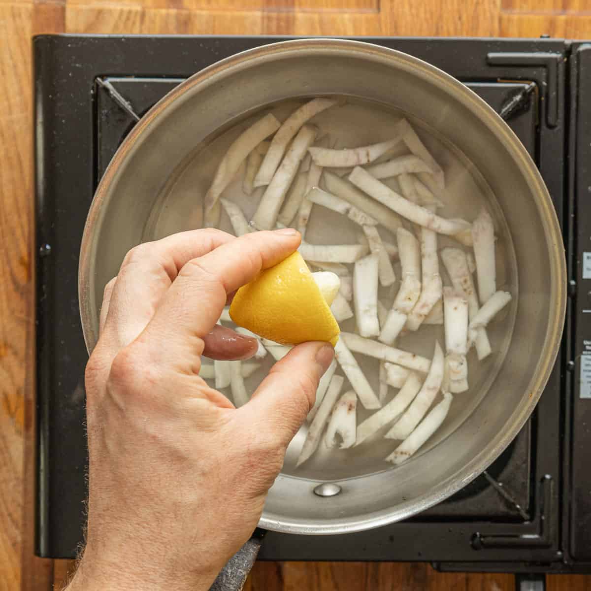 Cooking julienned thistle roots in salted lemon water. 