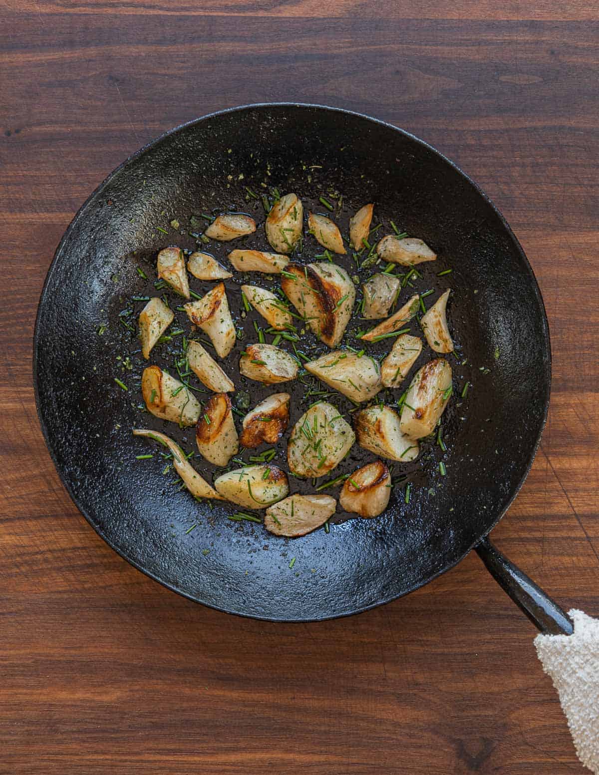 A pan of roasted thistle roots with ramp salt in a carbon steel pan. 