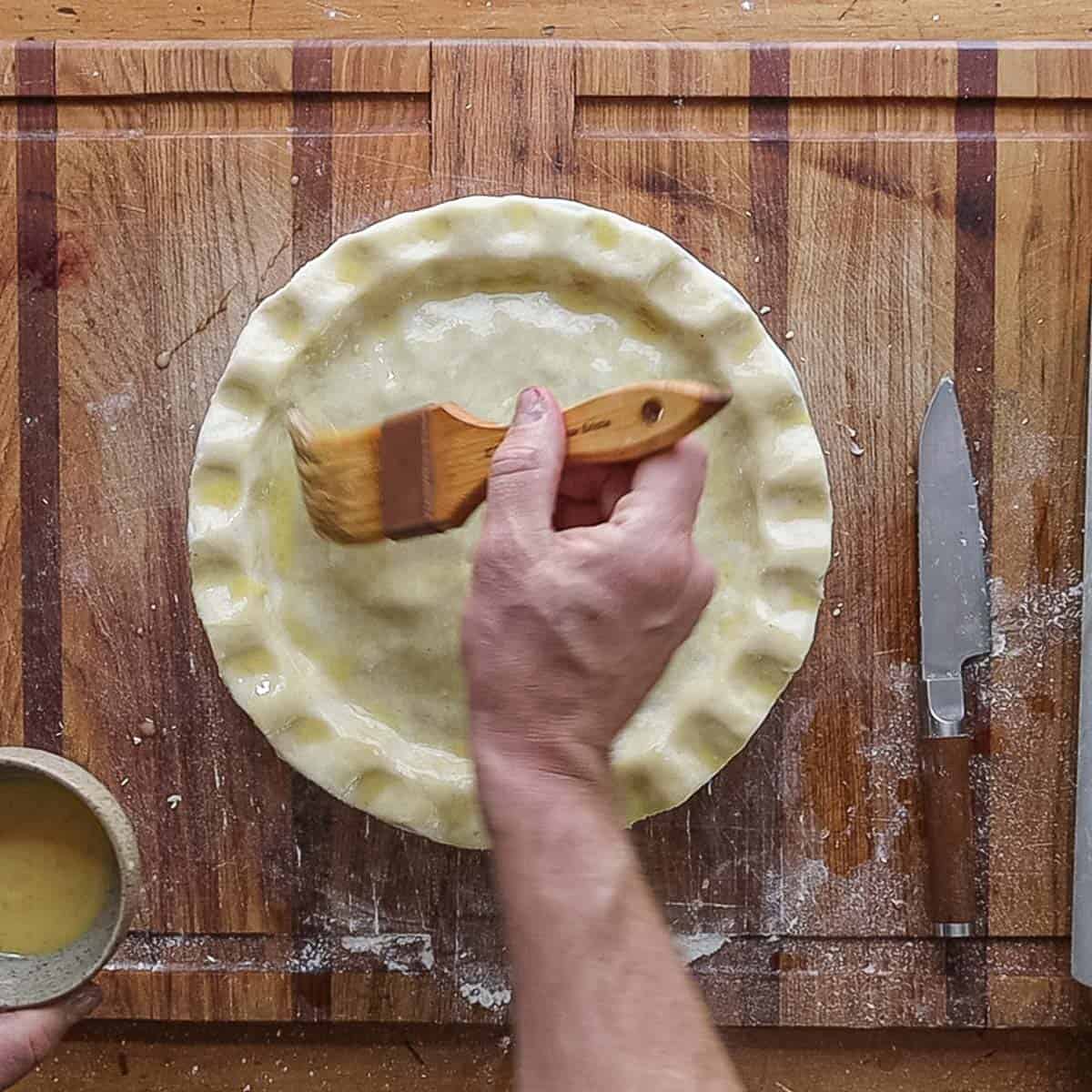 Brushing the top of a pie with egg wash. 