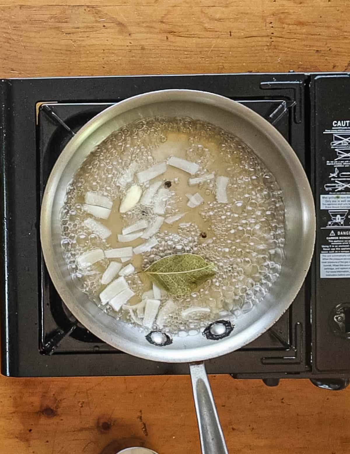 Reducing white wine and fish stock with a shallot, bay leaf, peppercorns and garlic. 