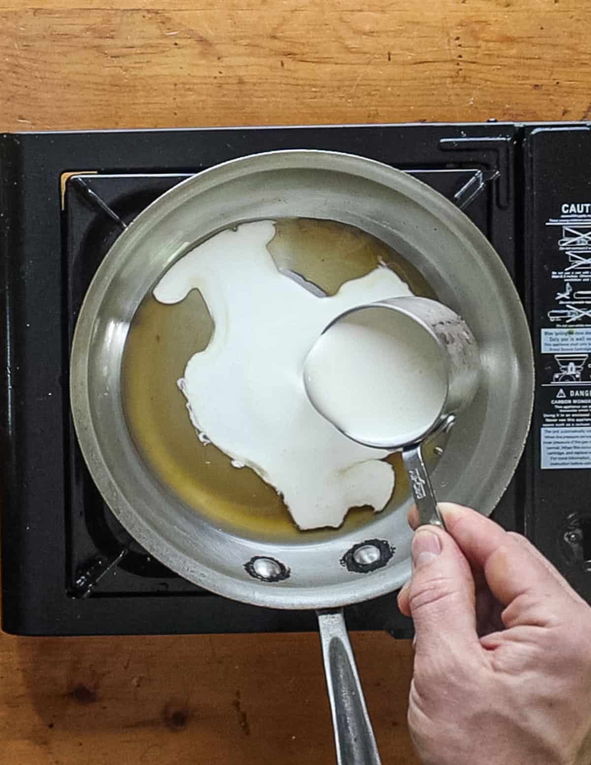 Adding cream to a reduction sauce. 