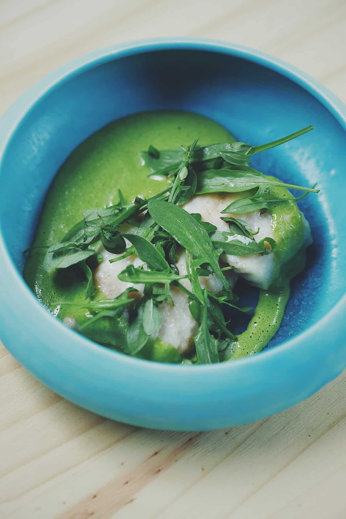 Two small pieces of whiefish next to green ramp sauce, sheep sorrel, dill, and chives. 