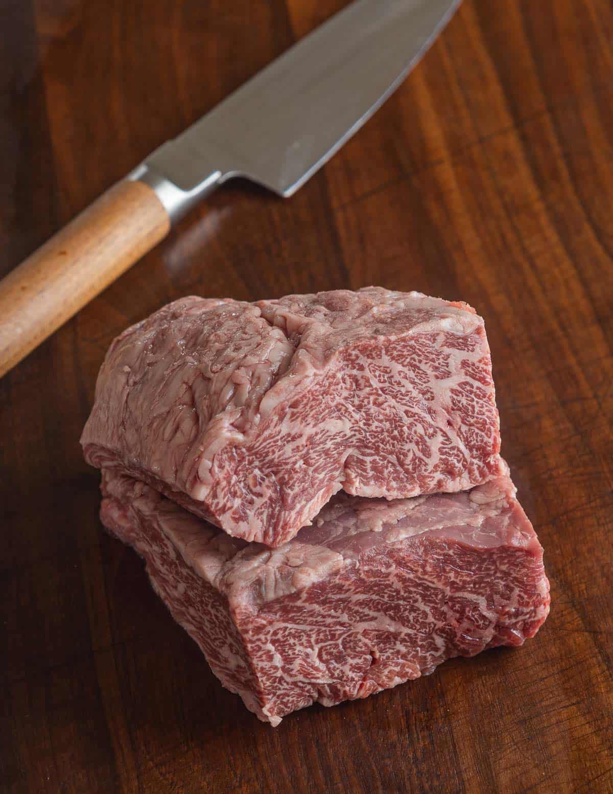 Two bavette steaks on a cutting board with a knife.