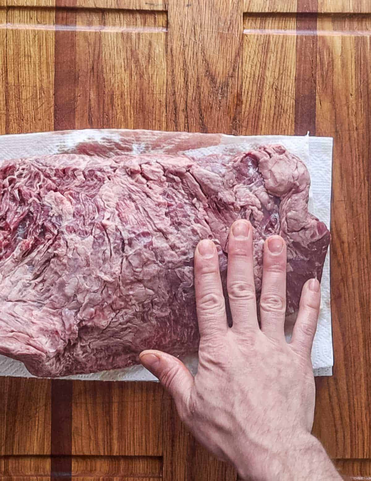 Patting a steak dry on paper towels before cooking.