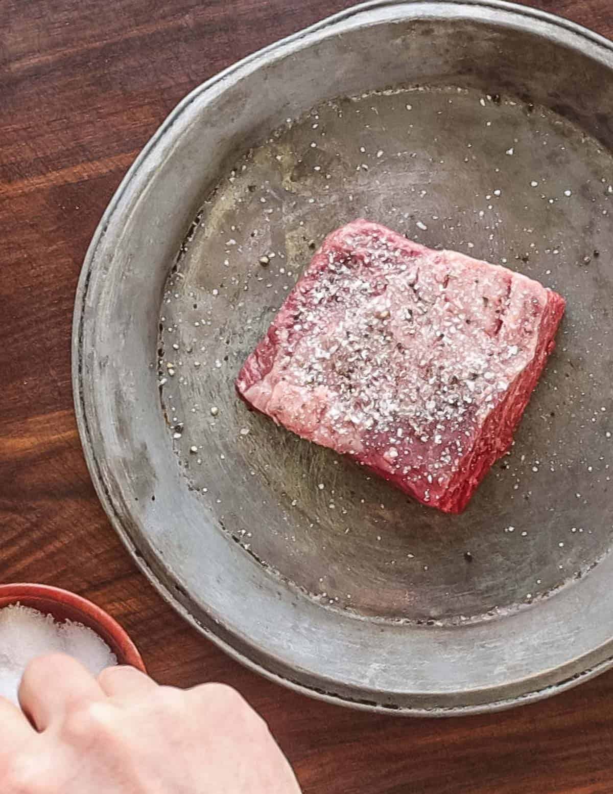 Dry brining a steak with salt and pepper before cooking.