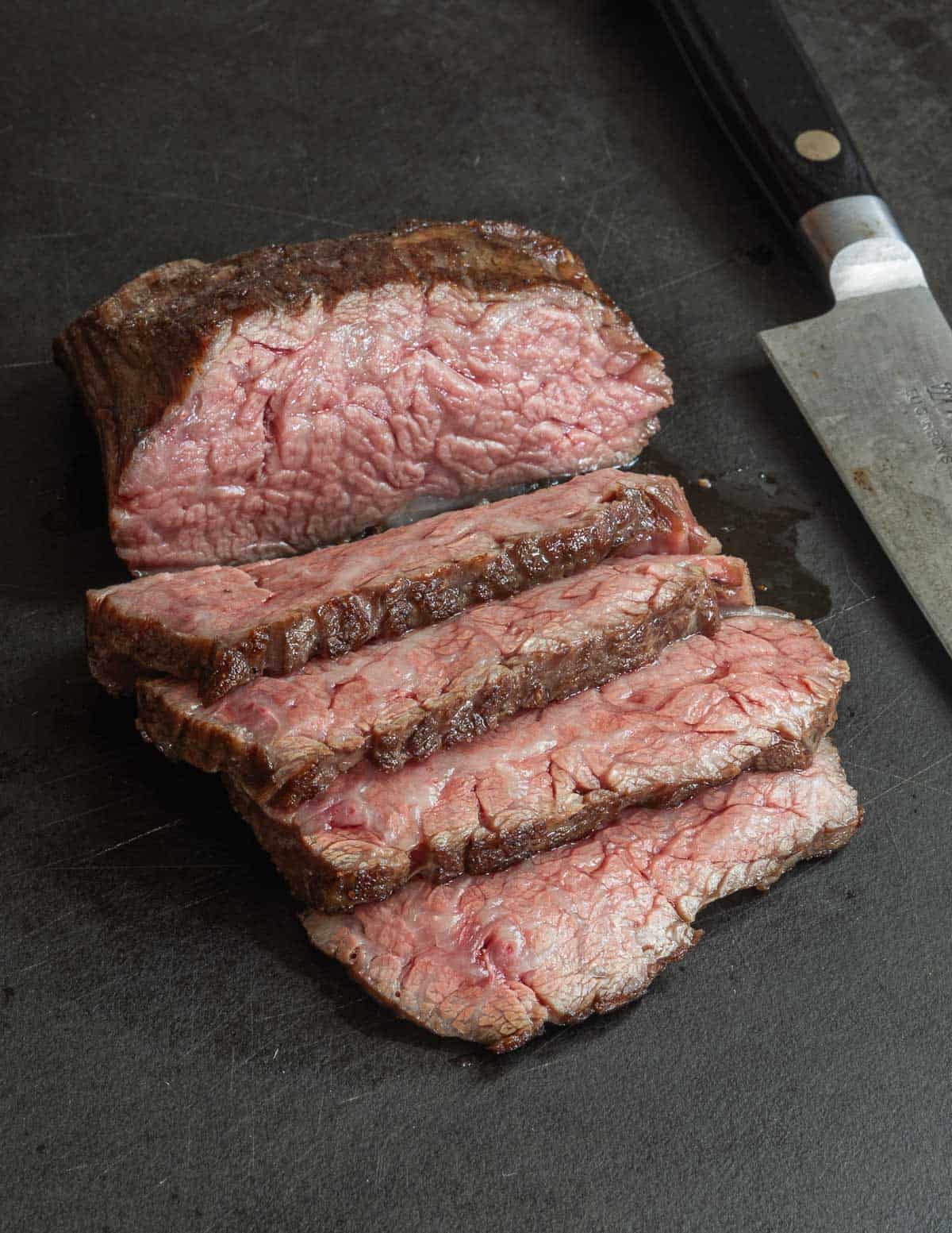 Cooked and rested bavette steak sliced on a cutting board.