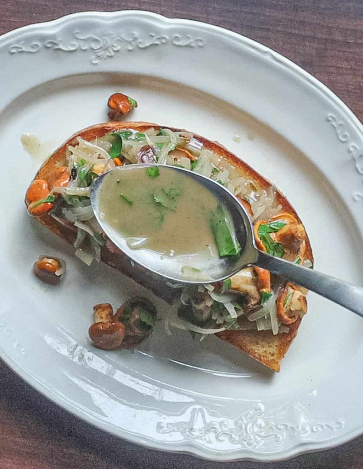 Spooning an herb butter sauce over bread with a spoon. 