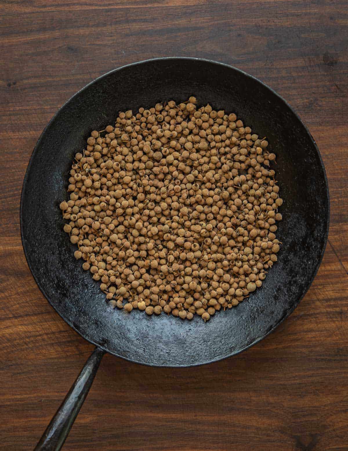 Brown roasted linden seeds in a kehoe carbon steel pan. 