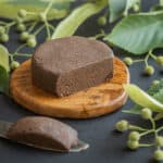 Linden chocolate on an olive wood coaster surrounded by basswood leaves and linden seeds.