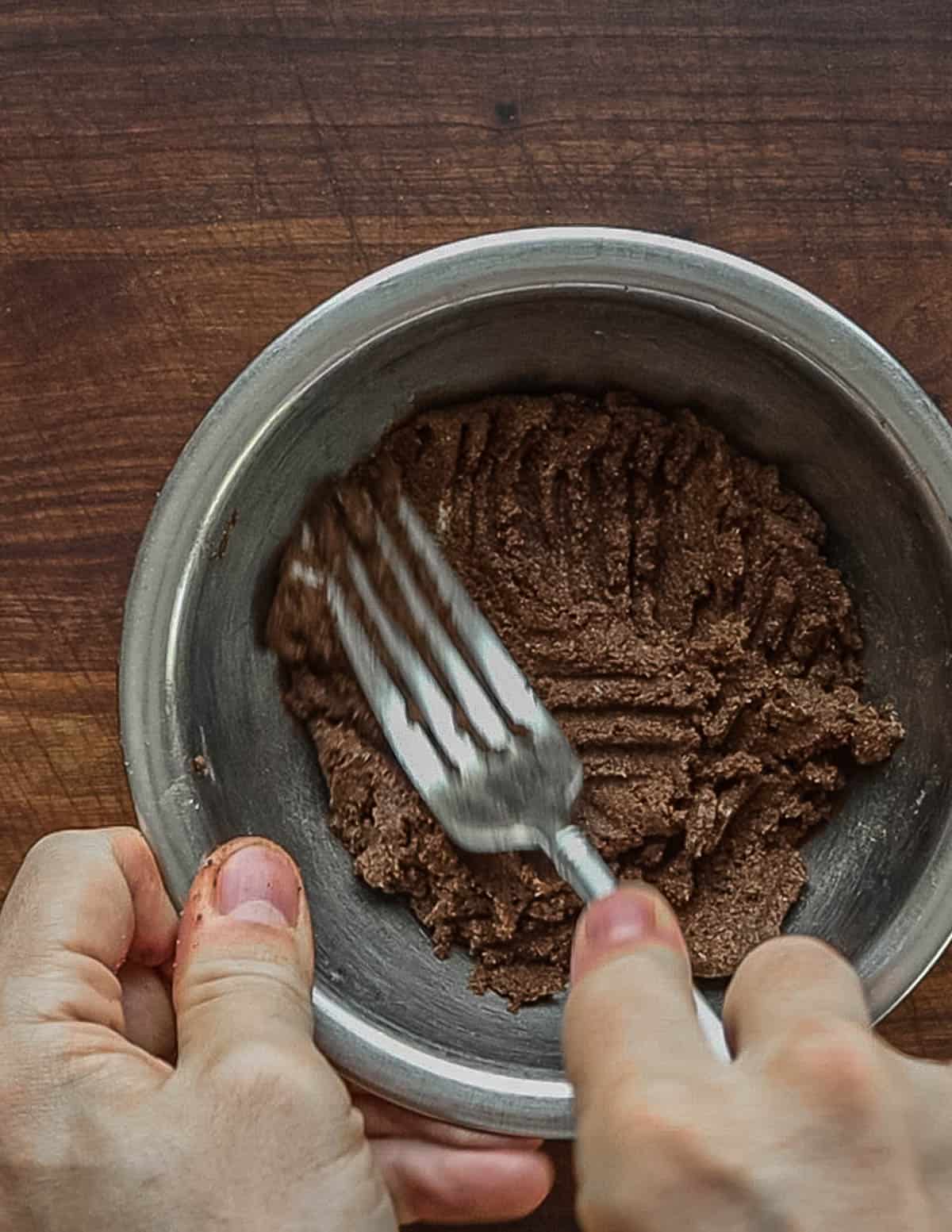 Finished linden seed chocolate being mixed with a fork in a metal bowl. 