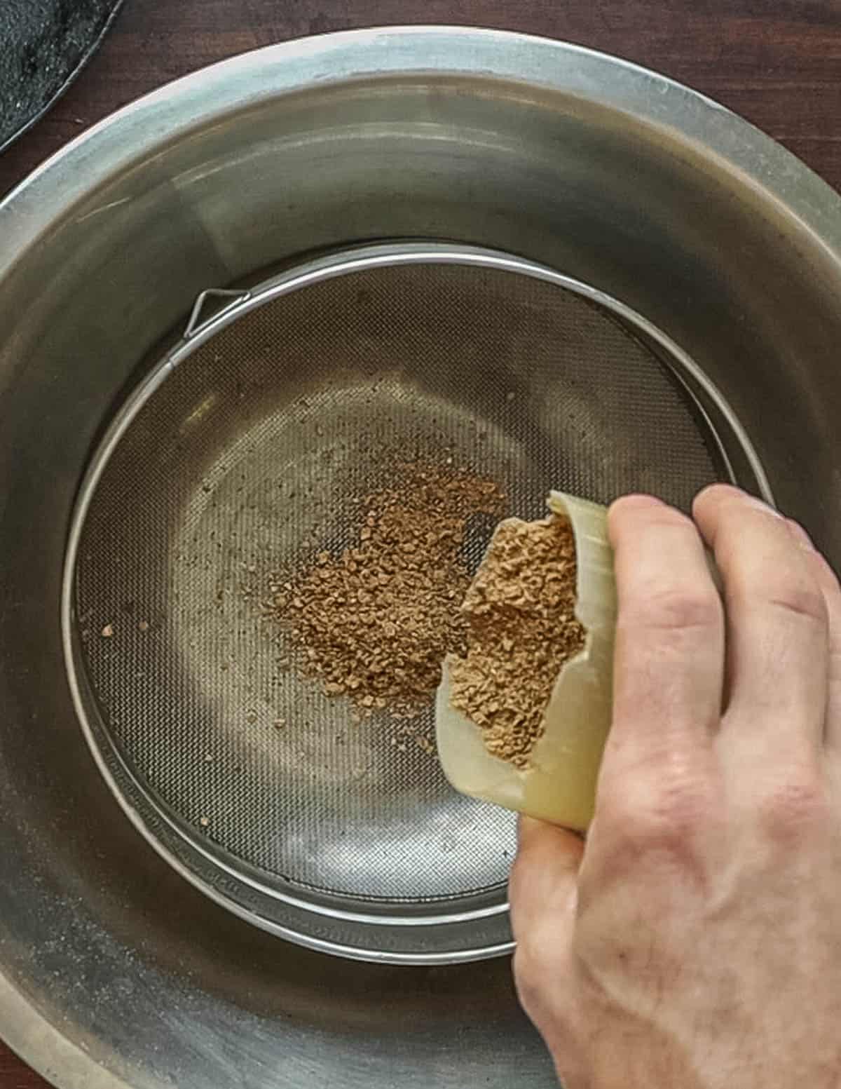 Sifting ground, roasted linden seeds through a tamis sieve. 