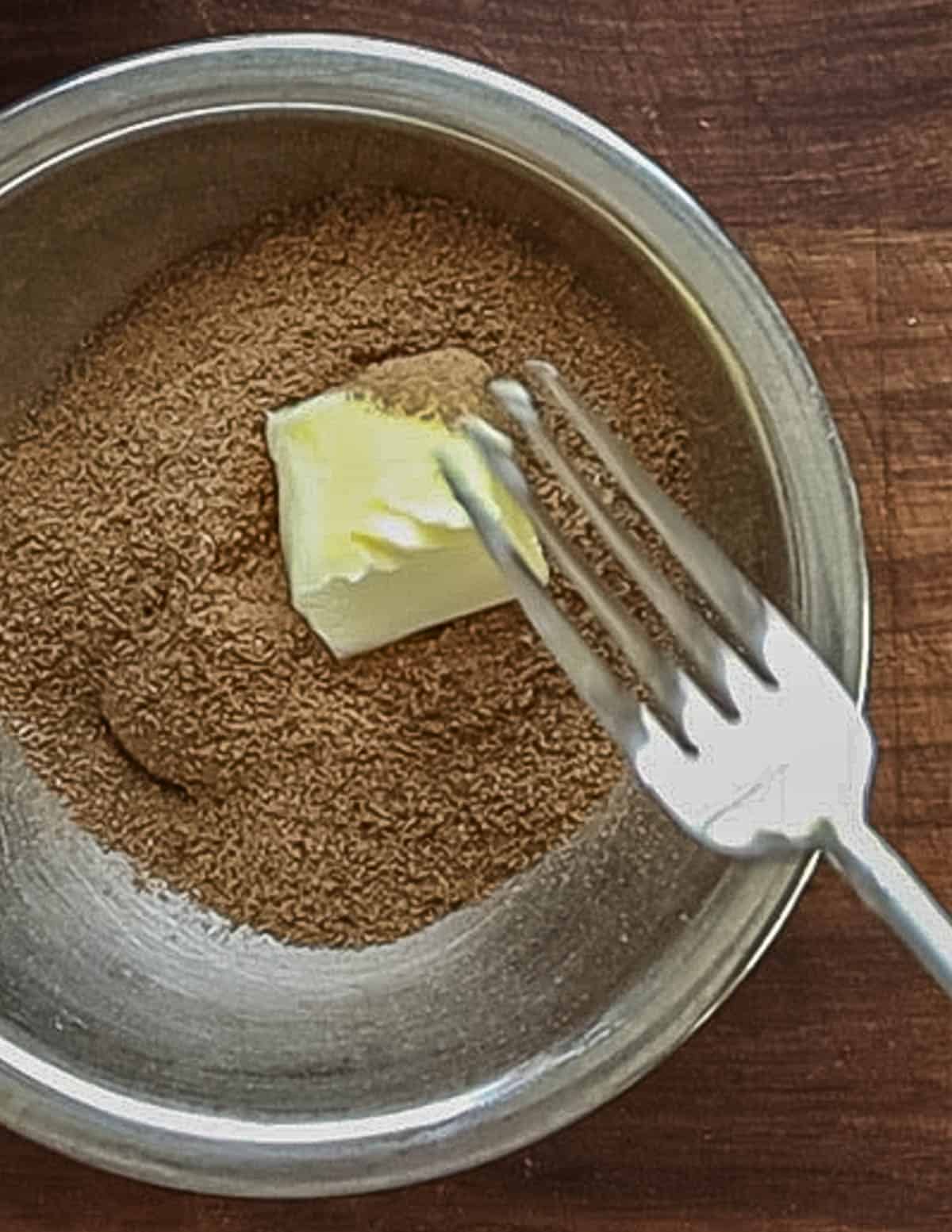 Mashing roasted linden seed powder with butter and sugar in a bowl with a fork. 