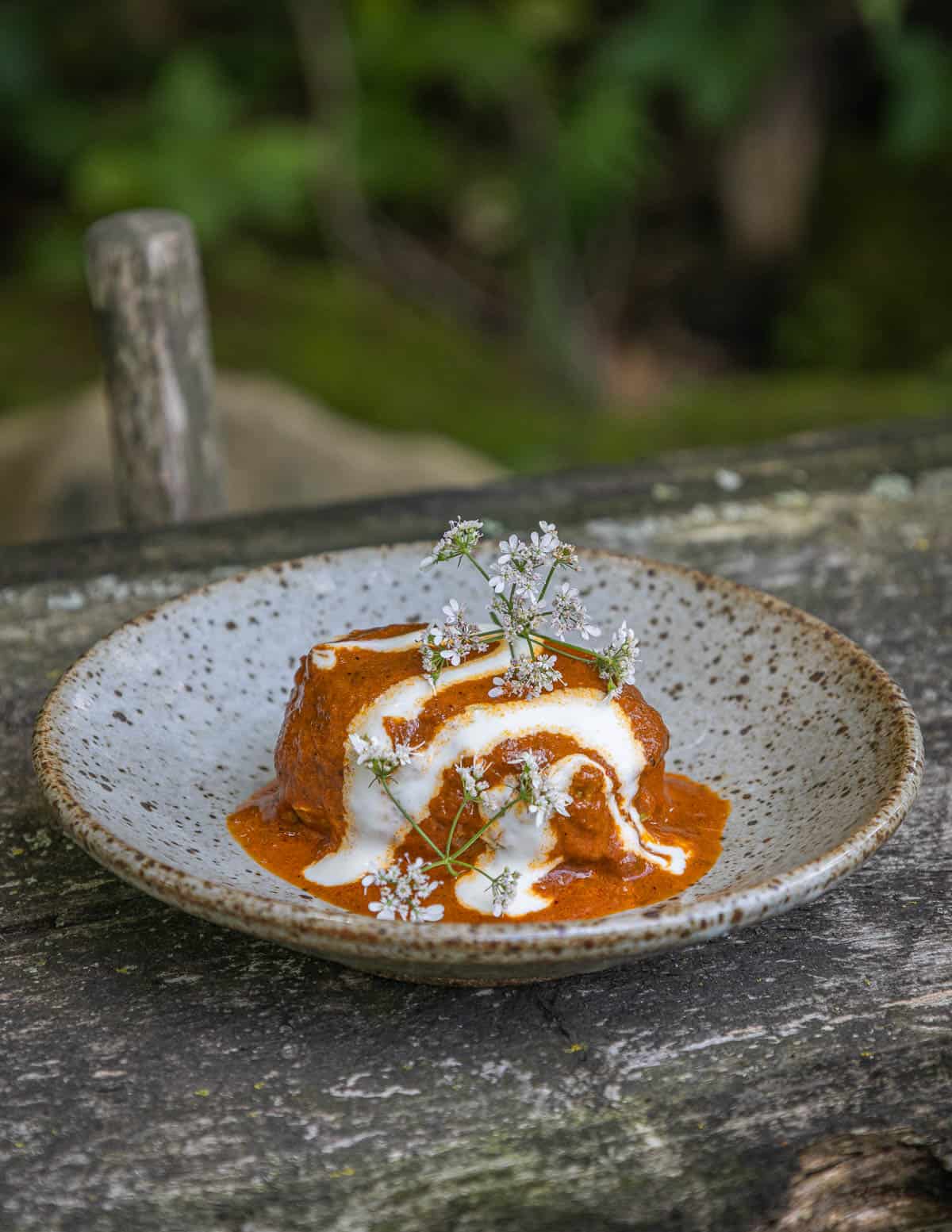 Huazontles in guajillo sauce garnished with cilantro flowers.