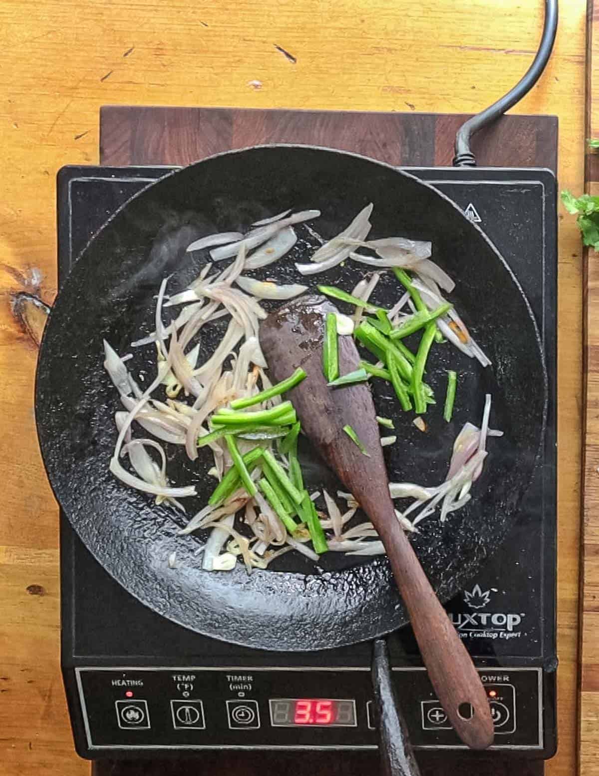 Adding sliced jalapeno to a pan with cooked shallots and garlic.