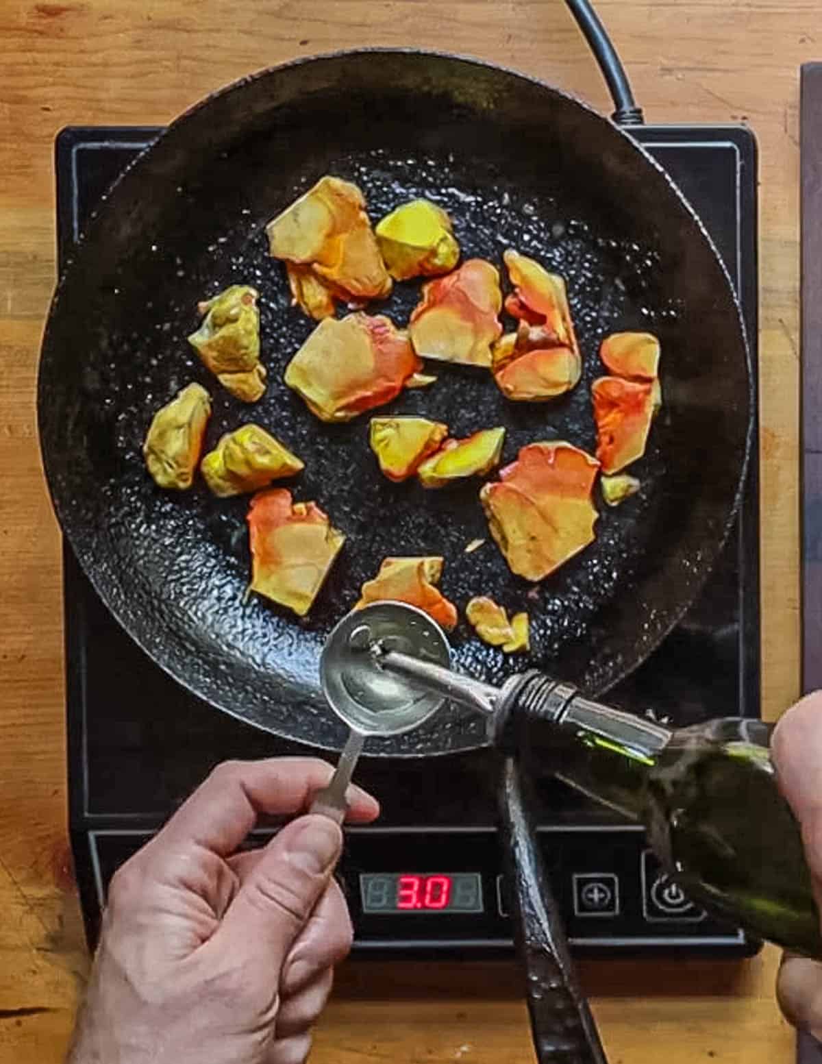 Adding oil to a pan of yellow and orange mushrooms cooking in a pan. 