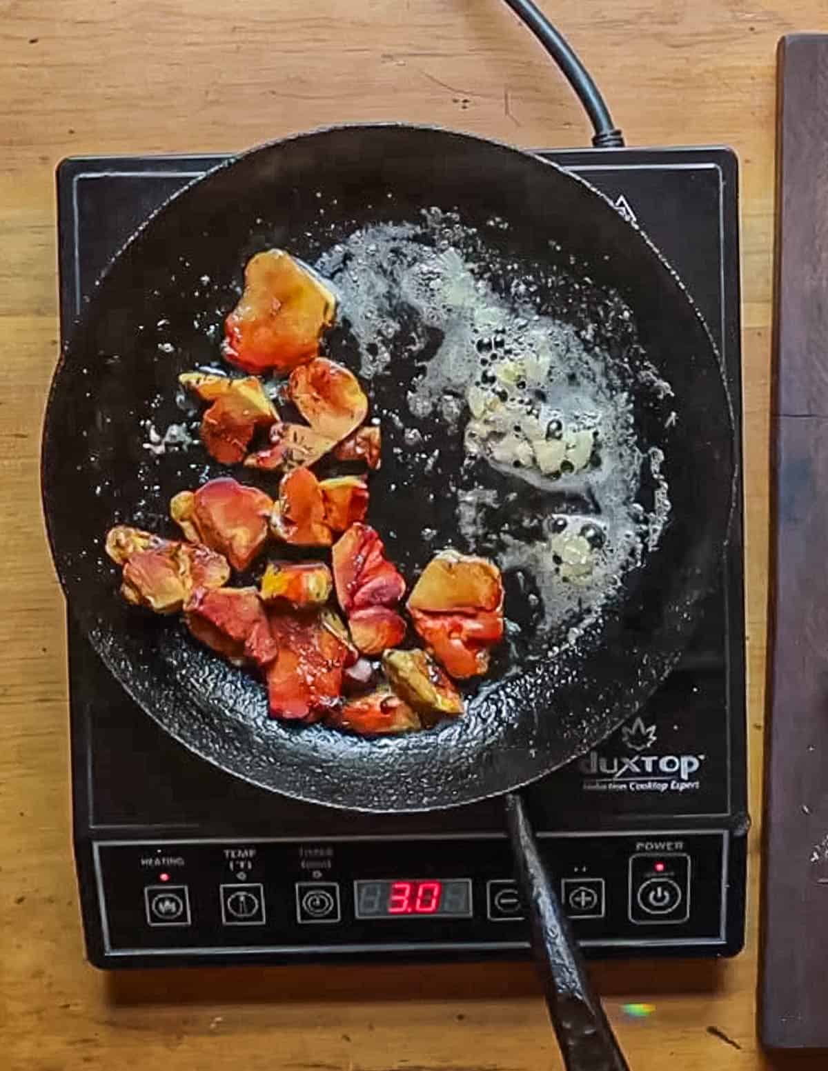 Adding garlic to a pan of yellow mushrooms cooking. 