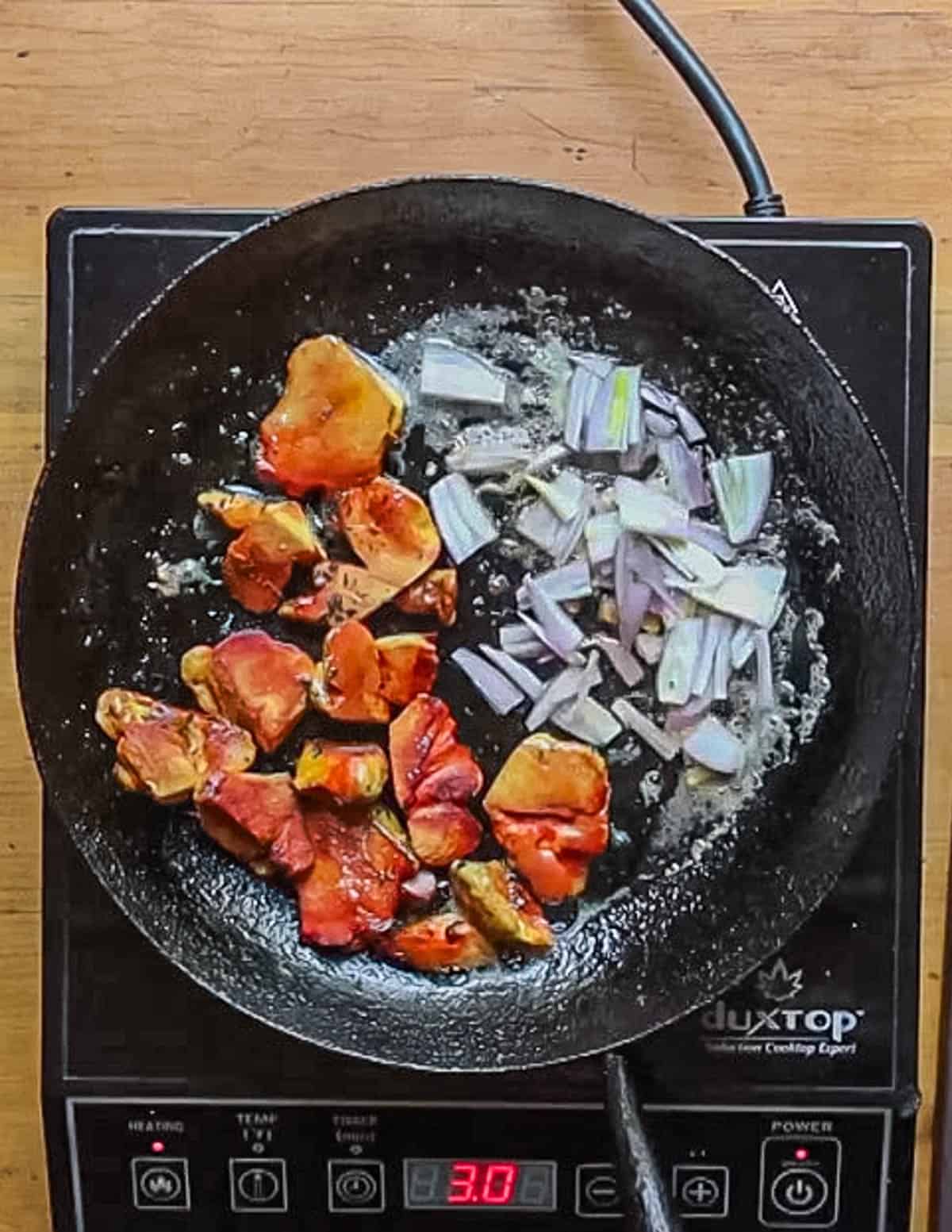 Adding shallots to a pan of yellow mushrooms cooking. 