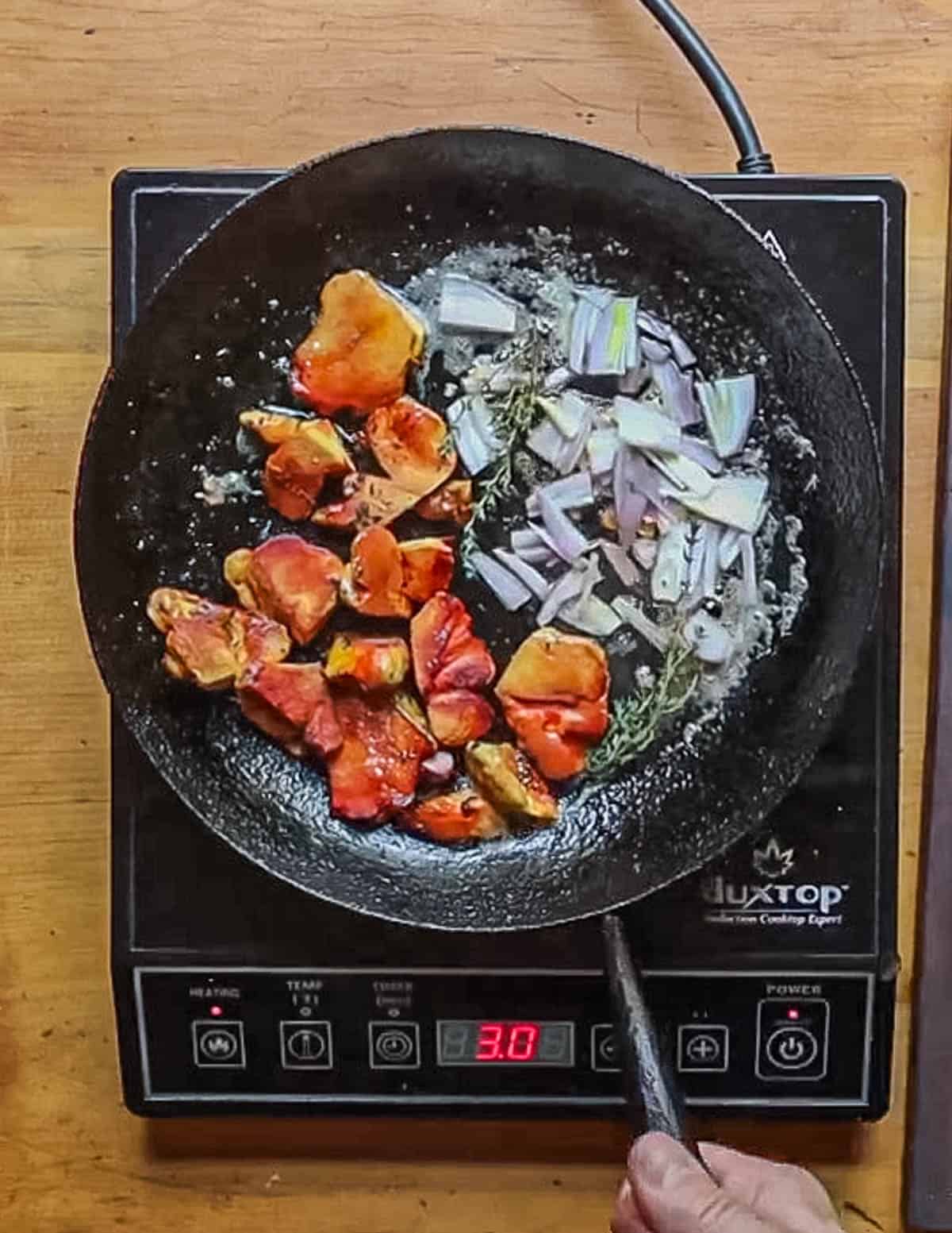 Adding fresh thyme sprigs to a pan of yellow mushrooms cooking. 