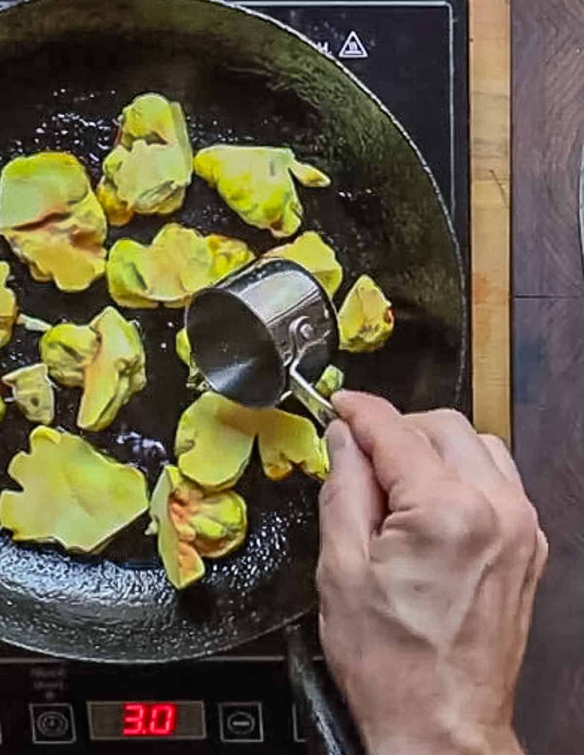 Pouring water into a pan of sliced yellow mushrooms. 