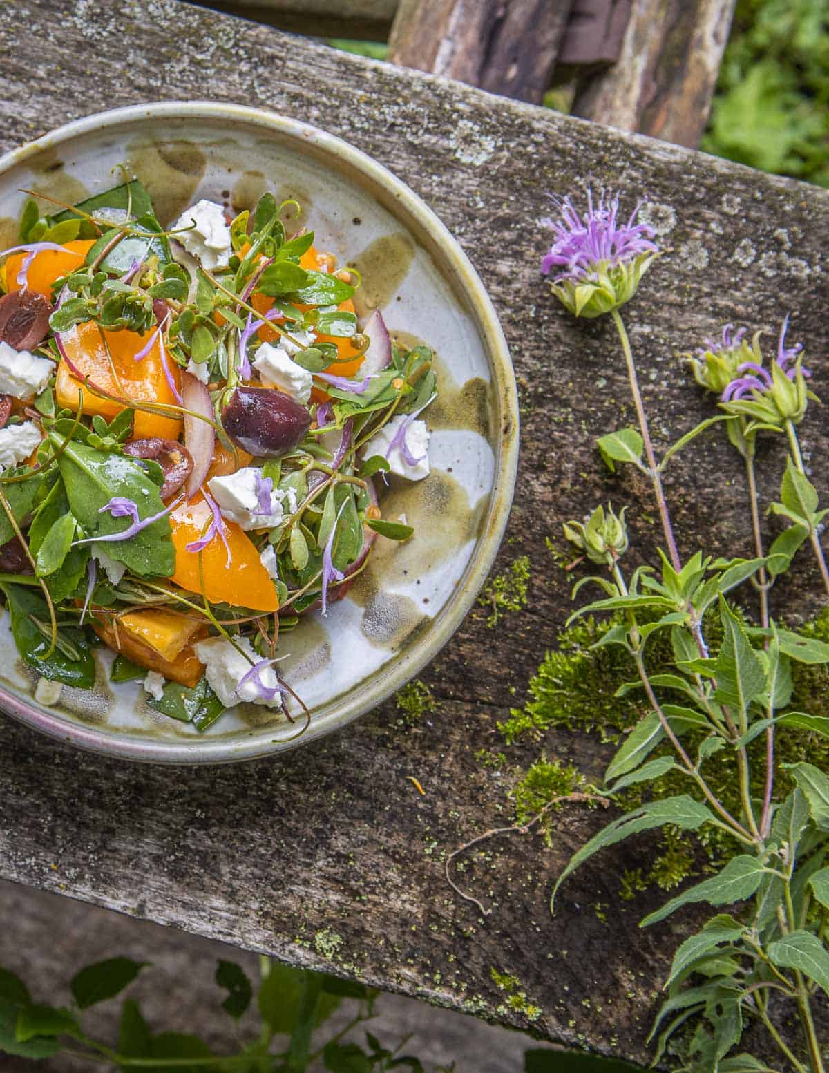 A Greek salad garnished with bee balm flowers. 