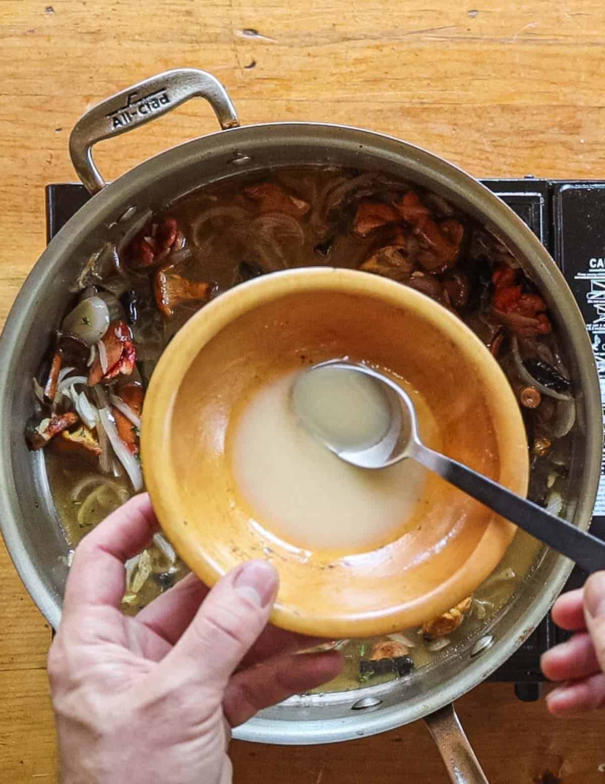 Adding roux to a pan of mushroom sauce. 