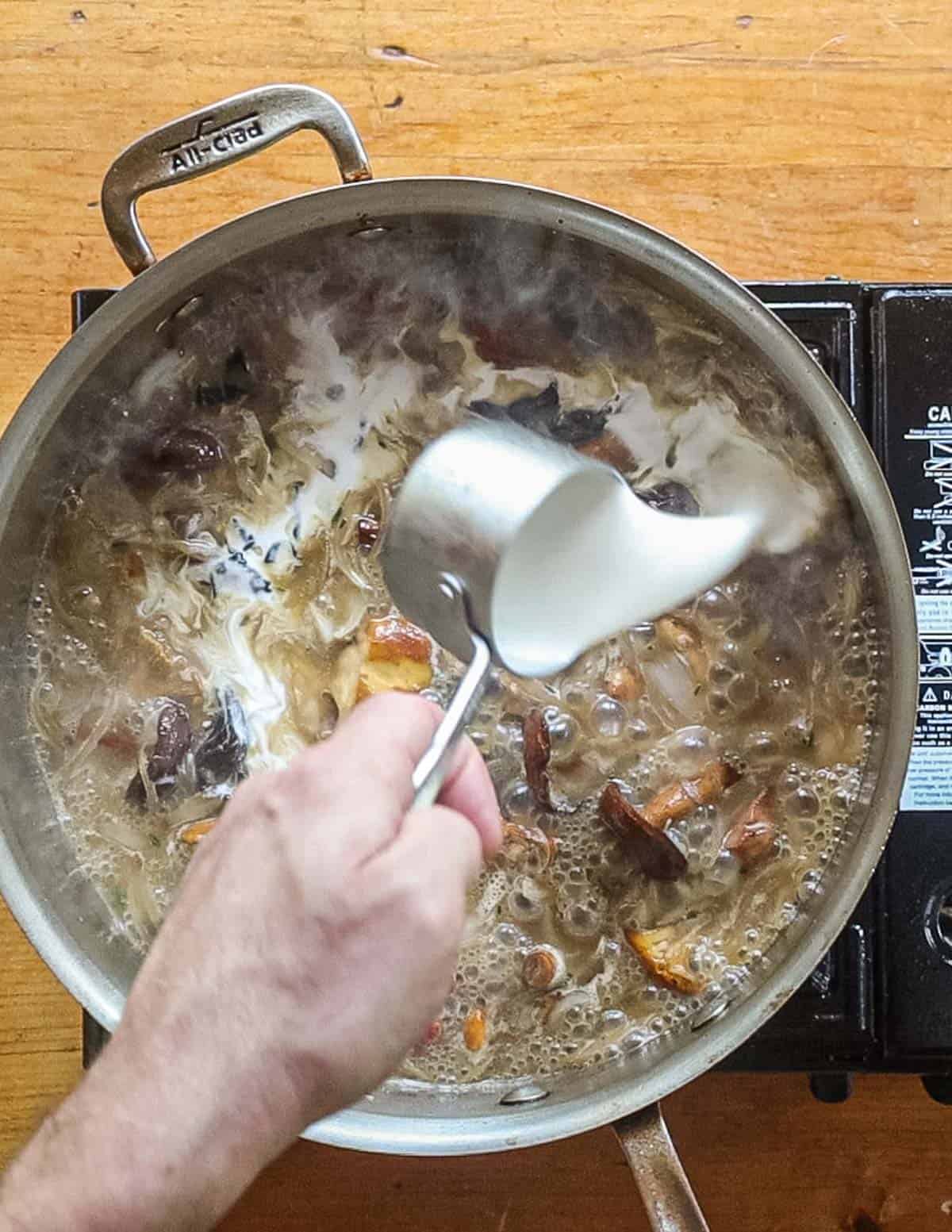 Adding cream to a pan of mushroom sauce. 