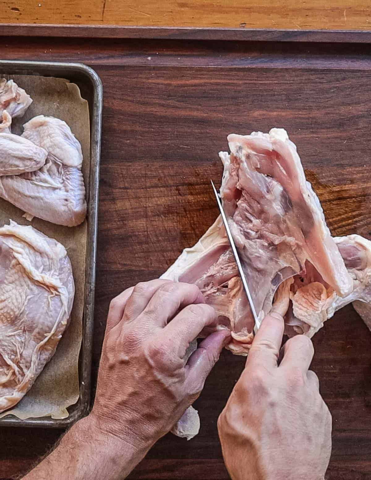 Cutting up a chicken and removing the legs. 