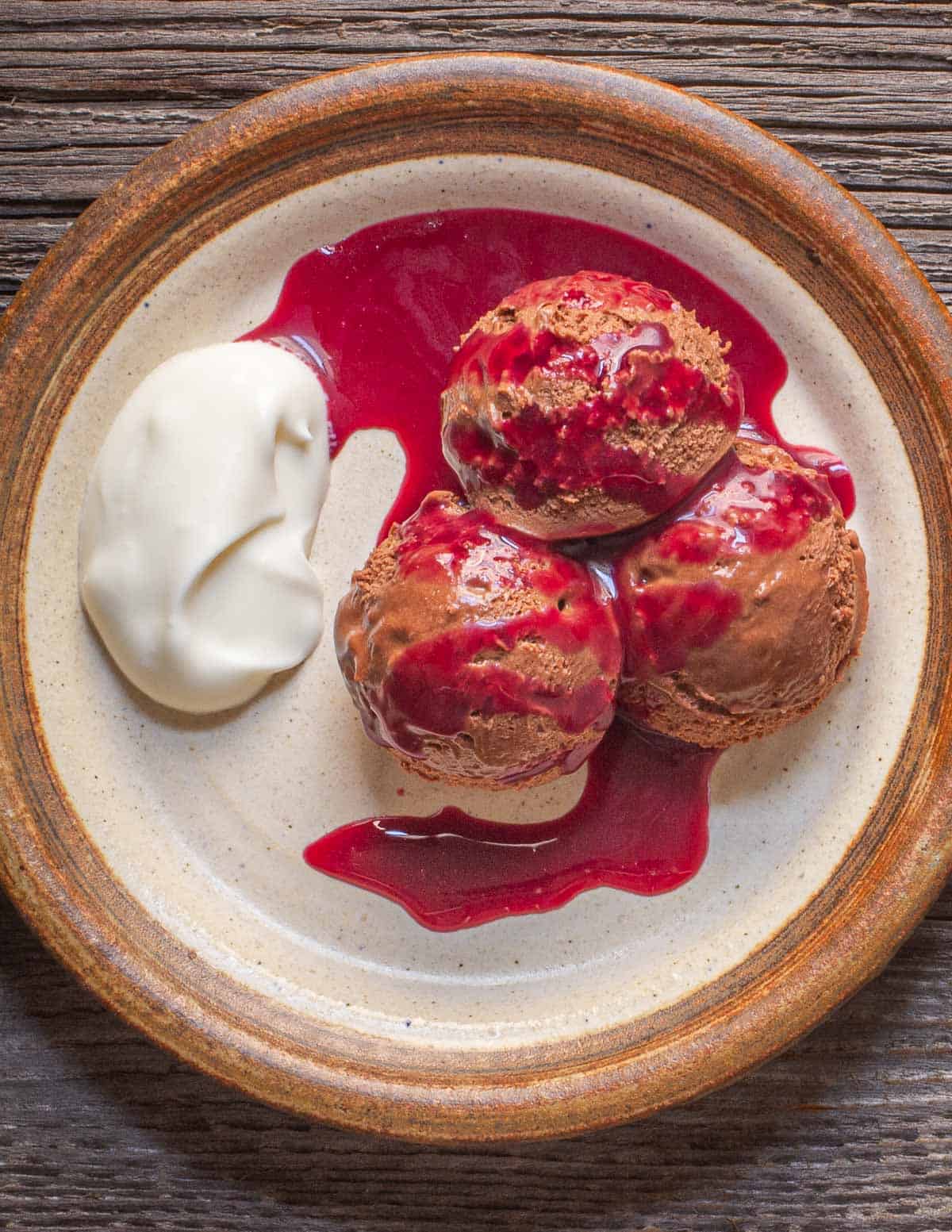 A plate of chocolate mousse with creme fraiche drizzled with wild cherry syrup. 