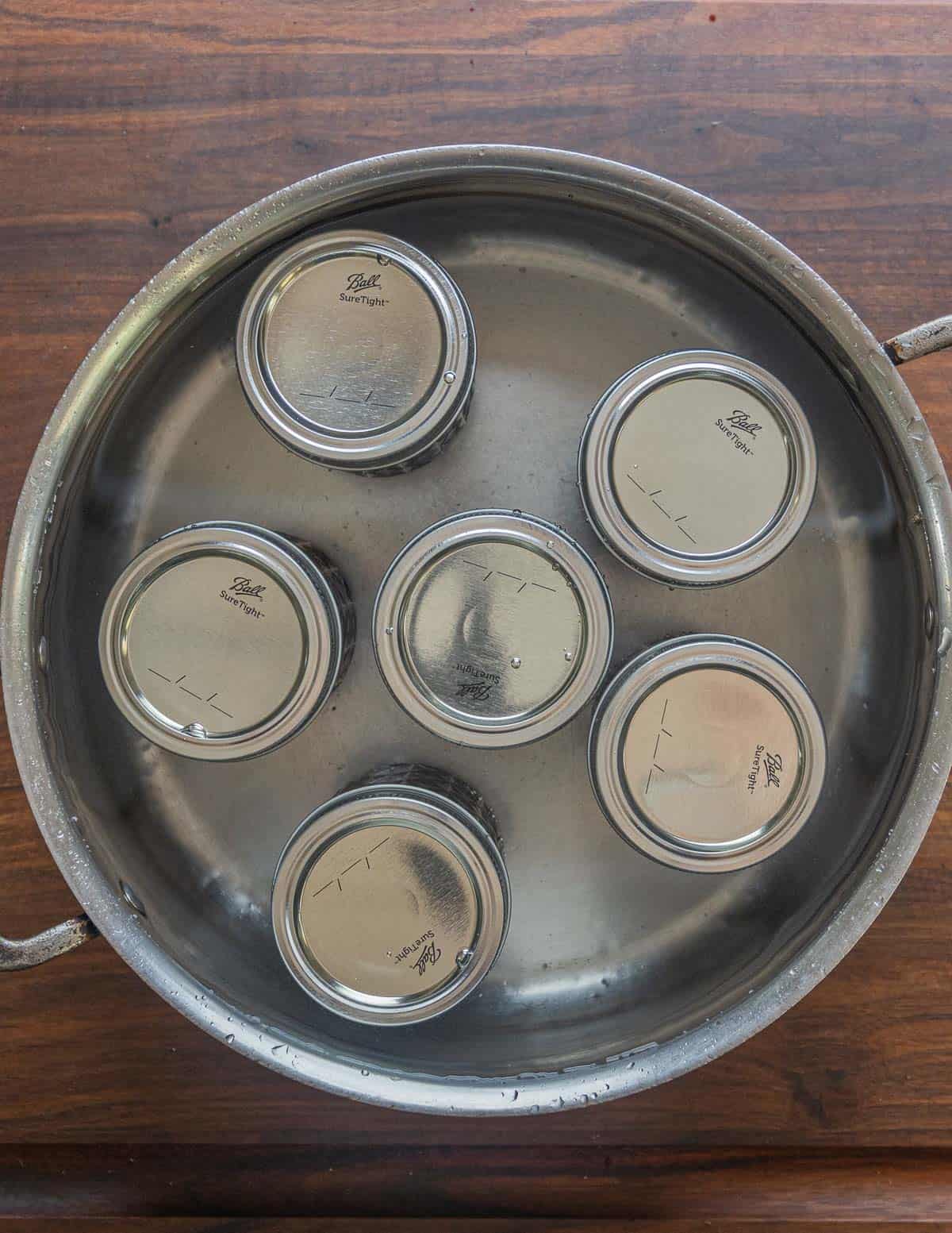 Mason jars in a pot covered with water ready for canning. 