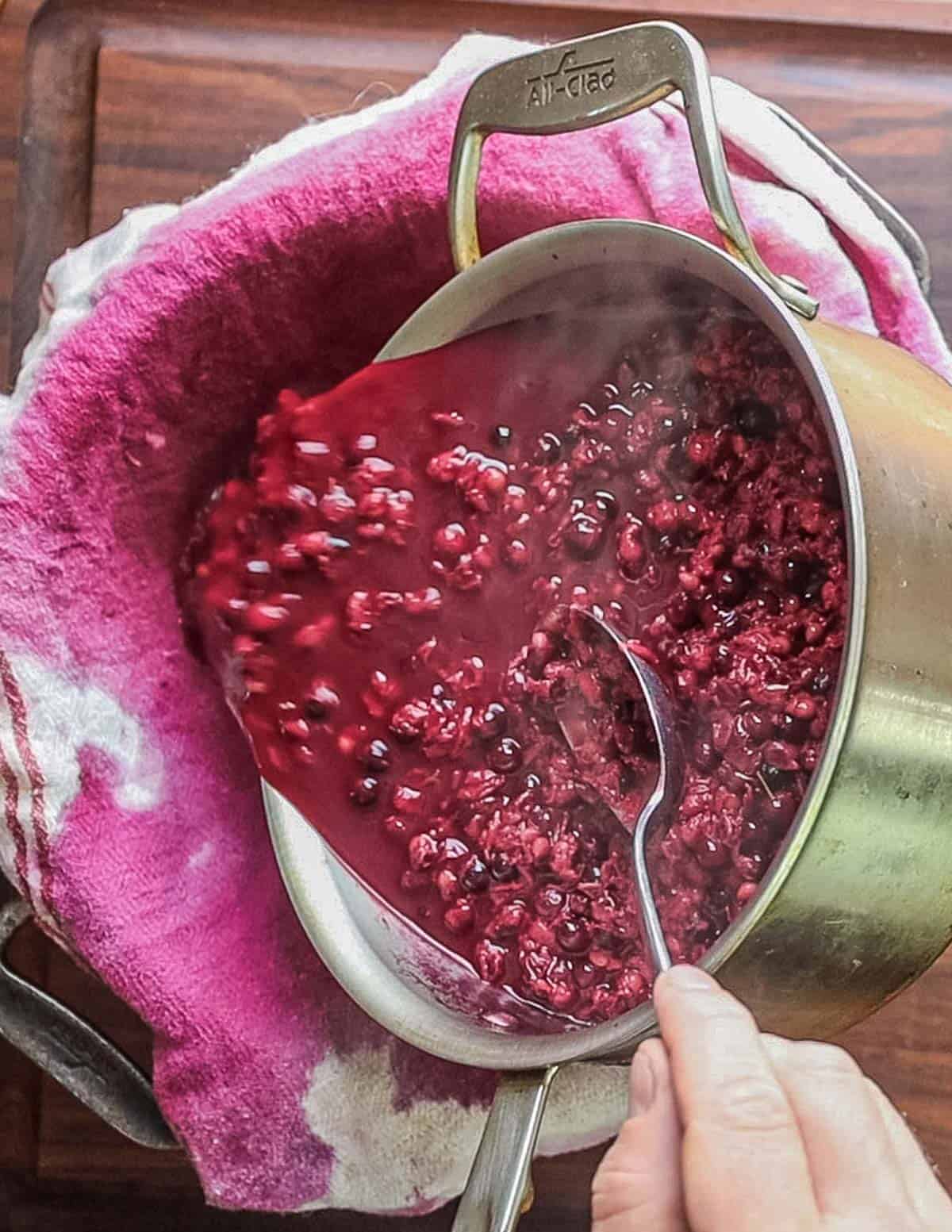 Pouring cooked wild cherries into a colander lined with cheesecloth. 