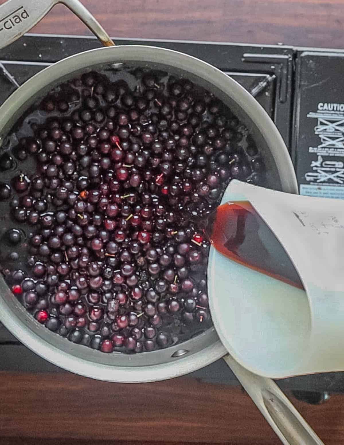 Adding water and vinegar to a pot of wild cherries. 