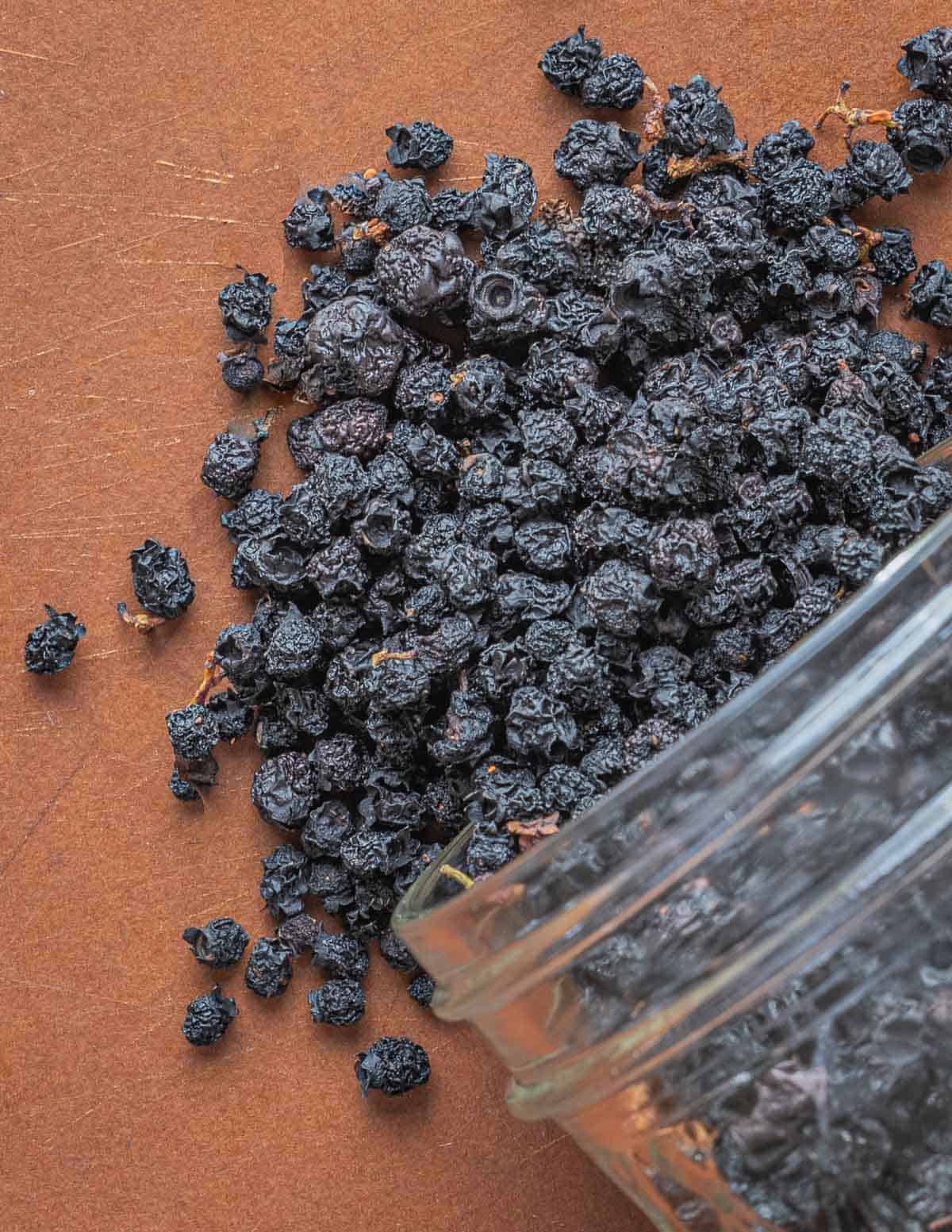 Dried wild blueberries pouring out of a glass jar. 