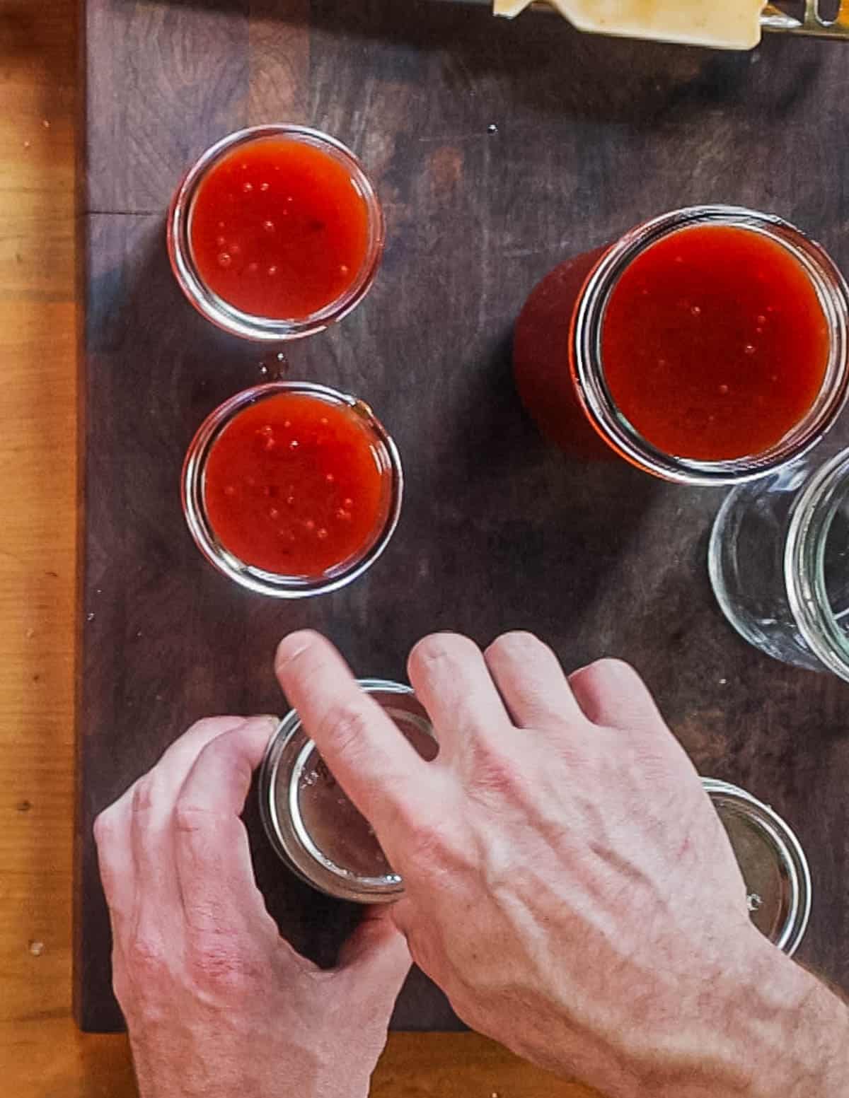 Screwing lids onto jars of wild plum jam. 