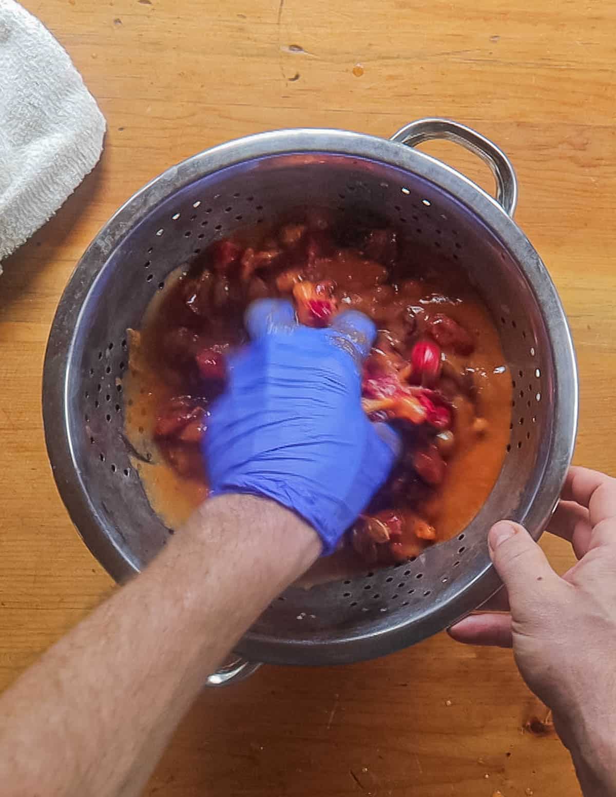 Pressing wild plum puree through holes in a colander. 