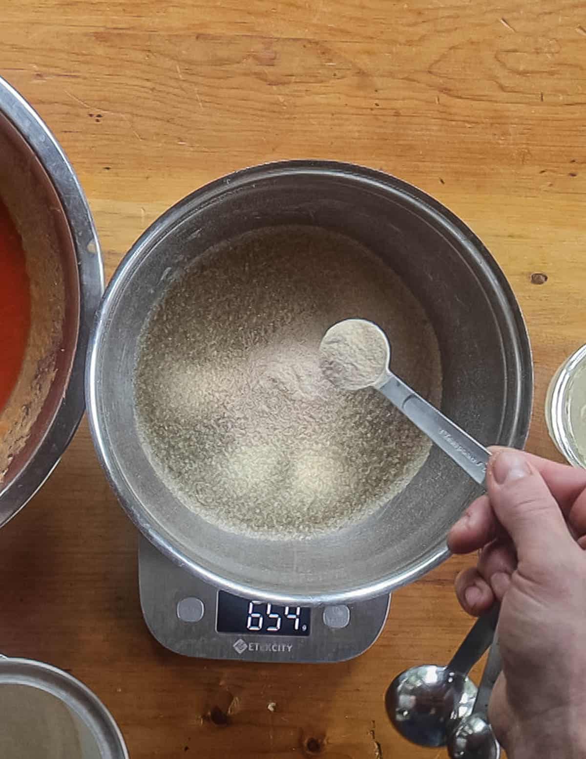 Adding a spponful of apple pectin to a bowl of wild plum puree. 