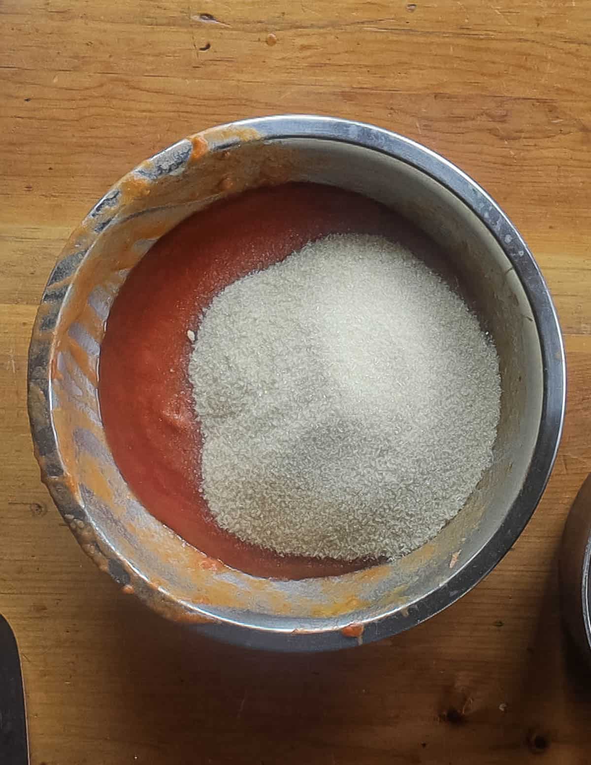 Adding sugar and pectin to a bowl of plum puree. 
