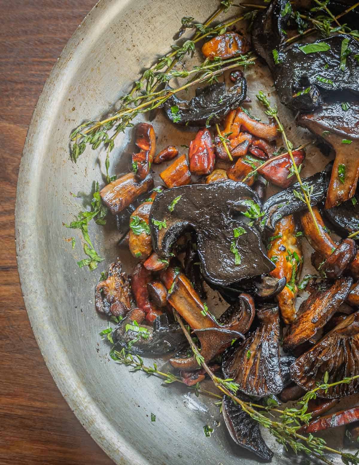 A large mix of sauteed mushrooms in a pan.