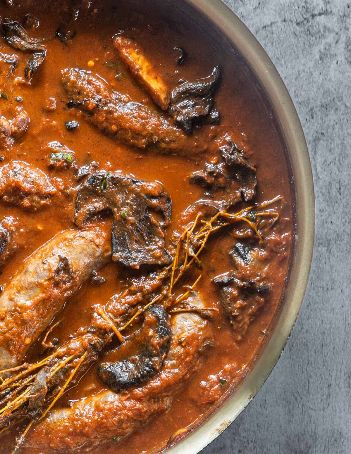 A pan of braised sausages with wild mushrooms. 