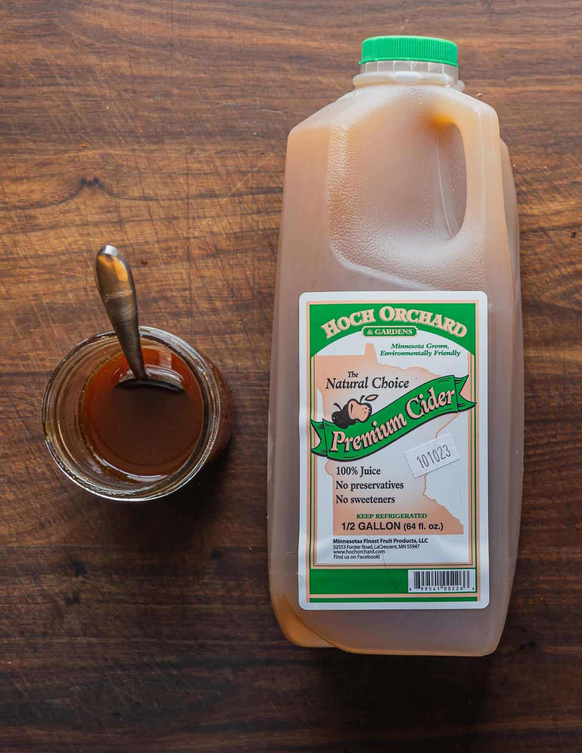 A bottle of local apple cider next to a jar of apple cider syrup. 